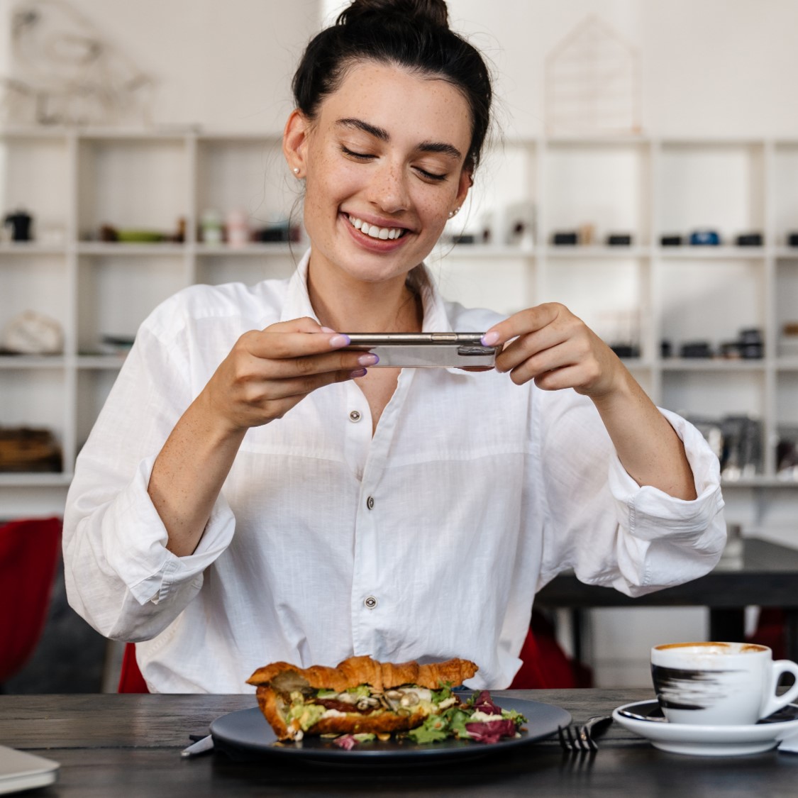 Photo d'une femme se filmant entrain de manger avec un plat au restaurant en direct en vidéo. Elle donne ses conseils et son avis sur l'application tested4you : des tests de produits et de lieux en vidéo UGC authentiques